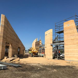 These rammed earth walls, under construction, were built by Olnee, the experienced rammed earth builders