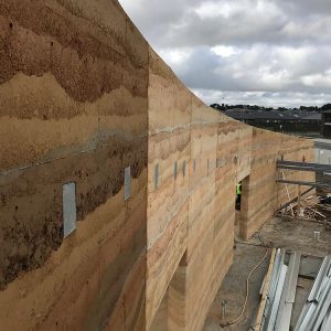 These rammed earth walls, under construction, were built by Olnee, the experienced rammed earth builders